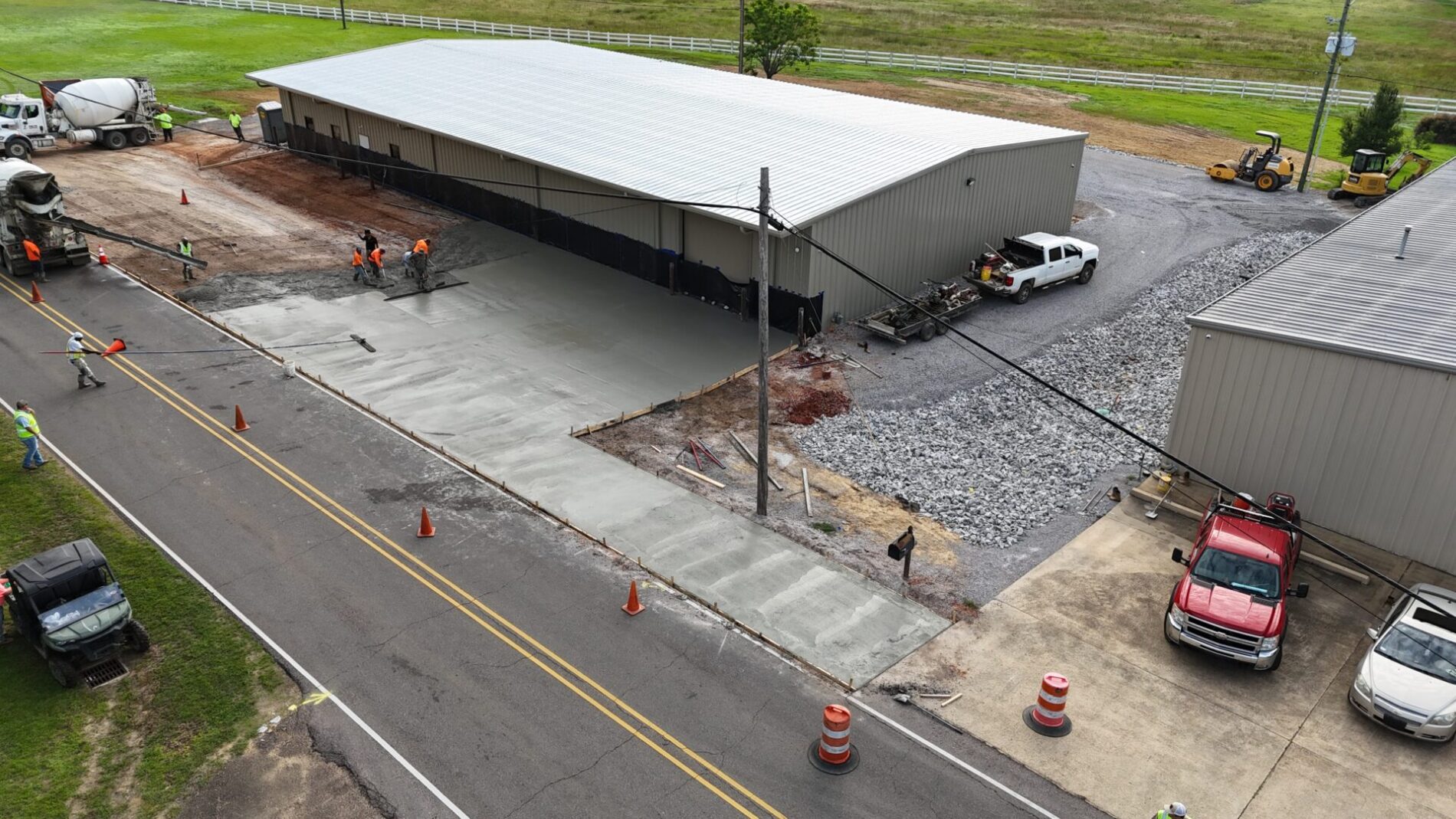 Workers smoothing freshly poured sidewalk by building
