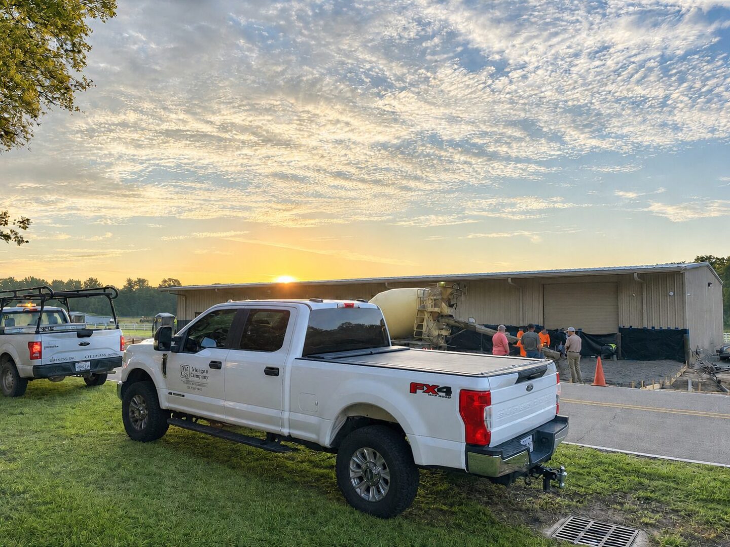Pickup trucks and concrete crew at sunrise